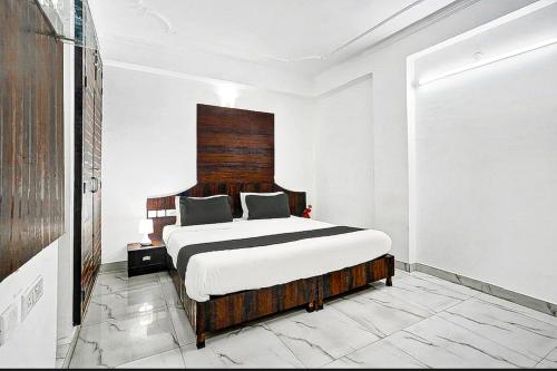 a bedroom with a large bed with a wooden headboard at COLLECTION O HOTEL SKY INN in Jaipur