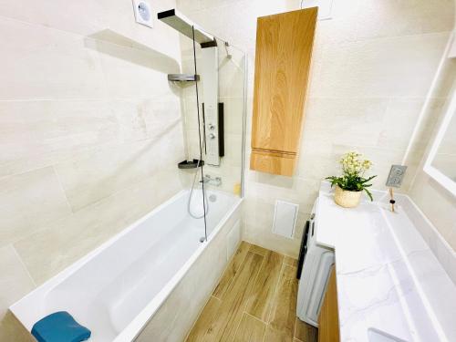 a bathroom with a white tub and a sink at L'élégant ~ T3 Lumineux et Moderne ~ Centre-ville in Vincennes