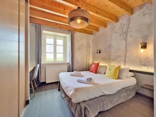a bedroom with a large white bed with colorful pillows at Logis Le Prieuré in Locronan