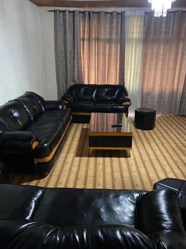 a living room with black leather couches and a coffee table at Golden motel in Gisenyi