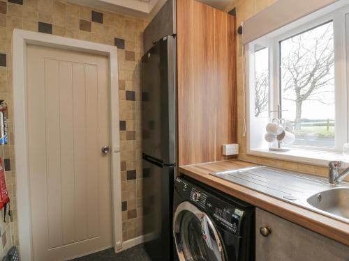 eine Küche mit einer Waschmaschine und einem Waschbecken in der Unterkunft Rosalin Cottage in Irvine