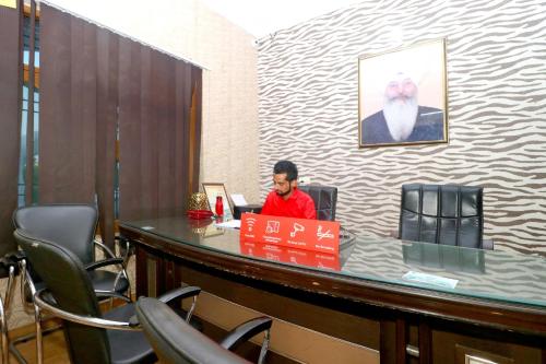 a man sitting at a desk with a laptop at OYO Flagship Sangam Resort in Shāhpur