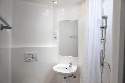 a white bathroom with a sink and a shower at Wenlock Court in Luton