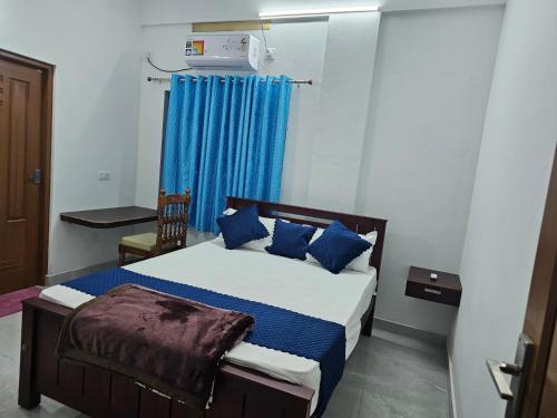 een slaapkamer met een bed met blauwe kussens bij ZEAL HOMES And Apartments Koothattukulam in Kuttāttukulam