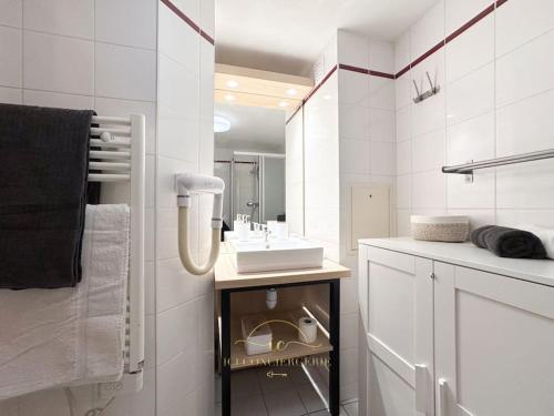 une salle de bain blanche avec un lavabo et un miroir dans l'établissement Le Cosy Saint-Cyr, à Saint-Cyr-lʼÉcole