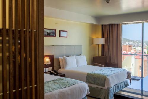 a hotel room with two beds and a window at SUNSOL UNIK Luxury Hotel in Porlamar