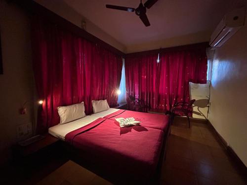 a bedroom with red curtains and a bed with a table at Hotel Prabha in Ratnagiri