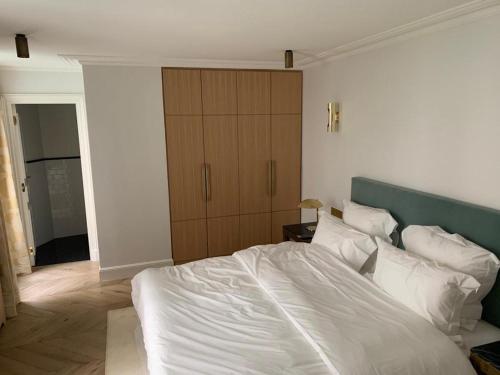 une chambre avec un lit blanc et une armoire en bois dans l'établissement L'appartement Des Arts, à Paris