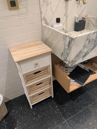 La salle de bains est pourvue d'une coiffeuse avec un comptoir en marbre et un lavabo. dans l'établissement L'appartement Des Arts, à Paris