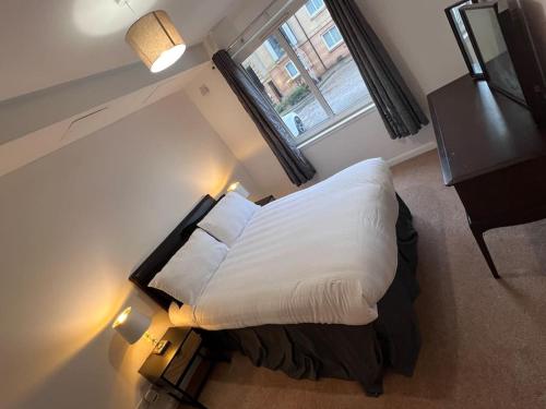 a bedroom with a bed with white sheets and a window at Infinity properties in Aberdeen
