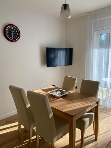 a dining room table with chairs and a clock on the wall at GO Jahorina by Olympic Gardens in Jahorina