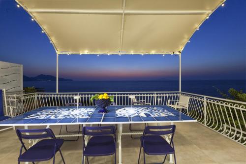 a table on a balcony with a view of the ocean at AMORE RENTALS - Villa Domus Franca in Massa Lubrense