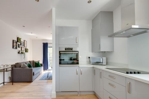 a kitchen with white cabinets and a living room at Stevenage Luxury 1 Bed Apartment Sleeps 4 WIFI Free Parking Secure by JM Short Lets in Stevenage