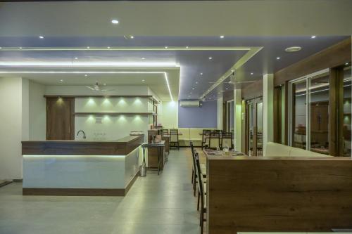 a restaurant with a bar with tables and chairs at Hotel Limelight in Kudal