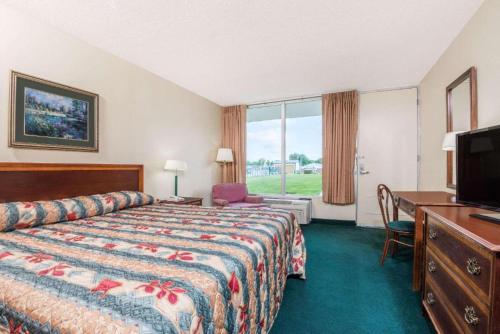 a hotel room with a bed and a desk and a television at BlissPoint Inn Wabash in Wabash