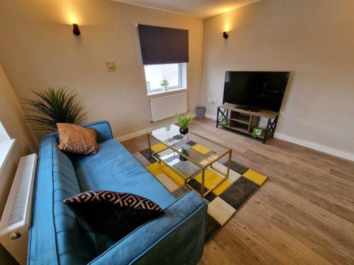 ein Wohnzimmer mit einem blauen Sofa und einem TV in der Unterkunft Vere Apartments in Cardiff