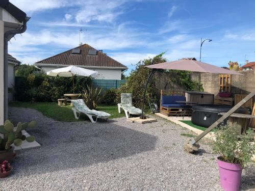 une arrière-cour avec deux chaises, un parasol et un grill dans l'établissement Chambre d hôte à la plage de 15 m2 LE MANAPANY, à Camiers