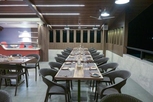 a long dining room with a long table and chairs at Hotel Limelight in Kudal