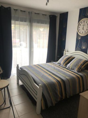 1 dormitorio con 1 cama con reloj en la pared en Chambre d hôte à la plage LE MANAPANY, en Camiers