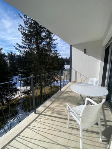 a patio with a white table and chairs on a balcony at GO Jahorina by Olympic Gardens in Jahorina