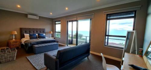 a bedroom with a bed and a couch and windows at Whale Watchers Paradise - 7 Sovereign Sands in KwaDukuza
