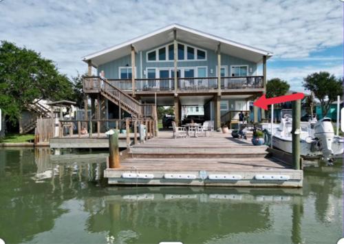 uma casa numa doca com um barco na água em Waterfront Guesthouse on Key Allegro/Little Bay with dock em Rockport