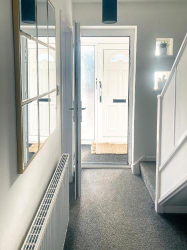 a hallway with a white door and a mirror at Phoenix House - 2 Double Bedroom House - Business and Corporate Travellers in Luton