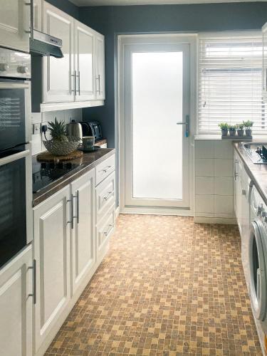 a kitchen with white cabinets and a tile floor at Phoenix House - 2 Double Bedroom House - Business and Corporate Travellers in Luton