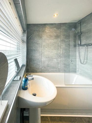 a bathroom with a sink and a bath tub at Phoenix House - 2 Double Bedroom House - Business and Corporate Travellers in Luton