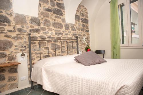 una cama en una habitación con una pared de piedra en U Campanin, en Dolceacqua