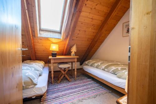 2 camas en una habitación con mesa y ventana en Chasa Rosa, en Vna
