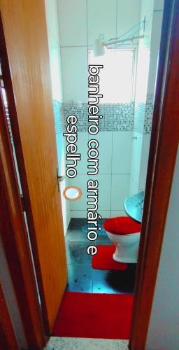 a bathroom with a toilet and a red rug at condomínio Alexandria in Belo Horizonte