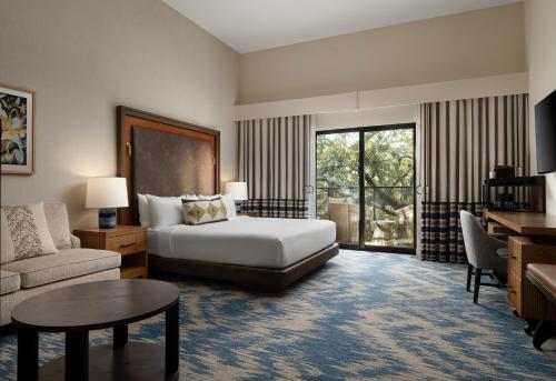 a hotel room with a bed and a couch and a table at Plaza San Antonio Hotel & Spa, Autograph Collection in San Antonio