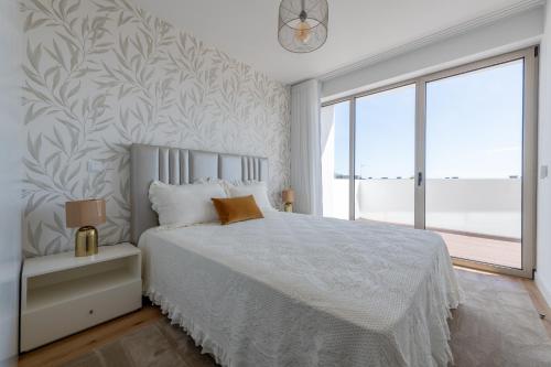 um quarto com uma cama branca e uma grande janela em The Princess Apartment no Funchal