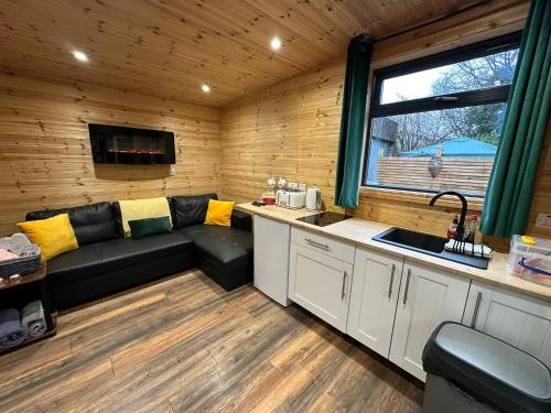 uma sala de estar com um sofá e um lavatório numa cabina em The Secret Garden - Hot Tub North Coast Stay em Garvagh
