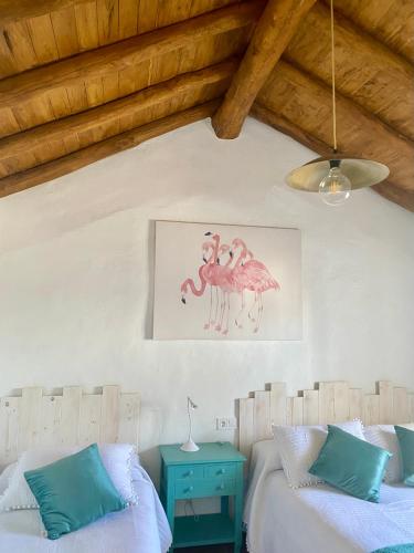 a bedroom with two beds and a painting on the wall at Casa Juan Harina in Setenil