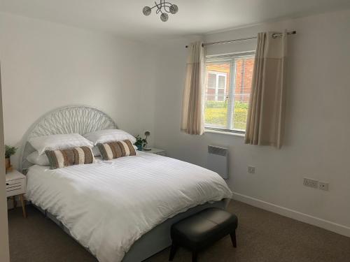 een slaapkamer met een bed met witte lakens en een raam bij Shepshed 2 Bedroom Apartment in Shepshed