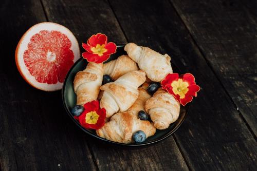 a bowl of pastries with flowers and blueberries and a grapefruit at Bed and Breakfast Kolo Adults only in Novigrad Istria