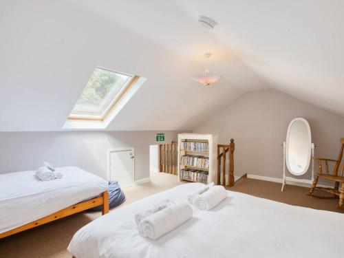 a attic bedroom with two beds and a window at Fernhill Cottage, Jurassic Coast in Charmouth