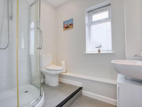 a white bathroom with a toilet and a sink at Fernhill Cottage, Jurassic Coast in Charmouth