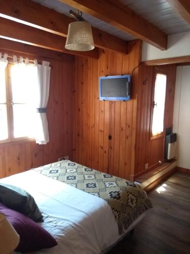 a bedroom with a bed and a tv on the wall at Cabañas Aitue in San Martín de los Andes