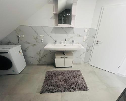 a white bathroom with a sink and a rug at Apartment Weikersheim I in Weikersheim