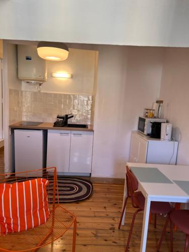 une cuisine avec des armoires blanches et une table et des chaises dans l'établissement Centre Historique Les toit du MOCO, à Montpellier