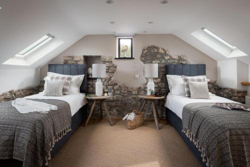 a bedroom with two beds and a stone wall at Lower Mill - 3 Bedroom - 5* Retreat - Llangennith in Swansea