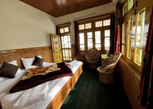 a bedroom with a bed and two chairs and windows at Sojhaholidayinn in Shoja