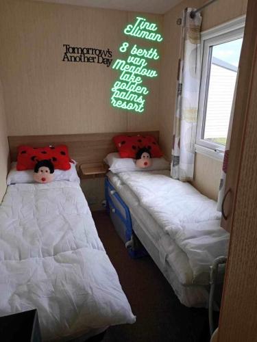 チャペル・セント・レオナルズにあるTina's caravan hireのベッド2台 小さな部屋 壁に書かれた文字