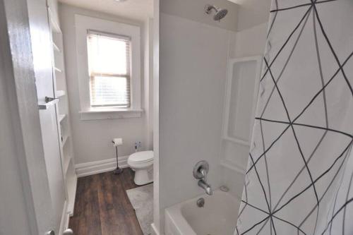 a white bathroom with a toilet and a shower at Housepitality - The Sail Away Townhouse in Columbus