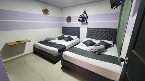 two beds in a small room with blue and white stripes at Aparta Hotel la 80 Estadio in Medellín