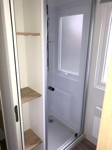 - une porte de douche en verre dans une petite salle de bains dans l'établissement Bungalow charmant à Canet-en-Roussillon avec piscine, à Canet