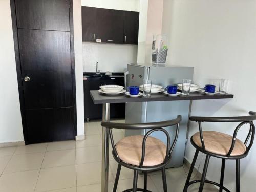 - une cuisine avec 2 chaises et une table avec de la vaisselle dans l'établissement Loft en San Fernando 303, à Cali